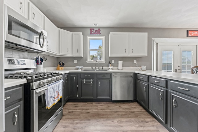 kitchen with stainless steel appliances, a sink, white cabinets, and light countertops