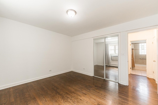 unfurnished bedroom with a closet, dark wood-type flooring, and baseboards