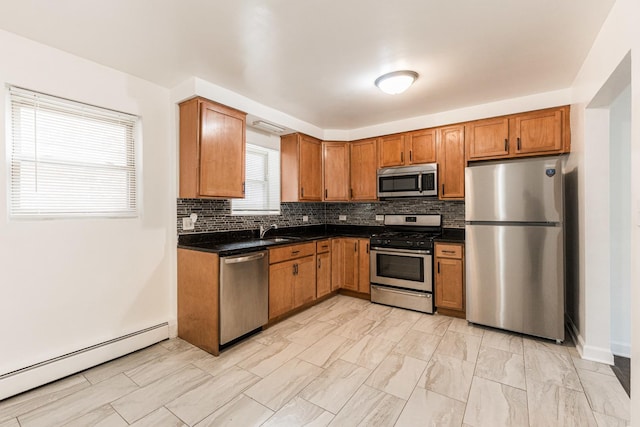 kitchen featuring stainless steel appliances, a baseboard heating unit, dark countertops, and a sink
