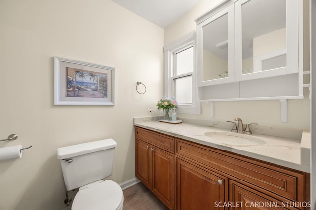 bathroom featuring toilet, vanity, wood finished floors, and baseboards