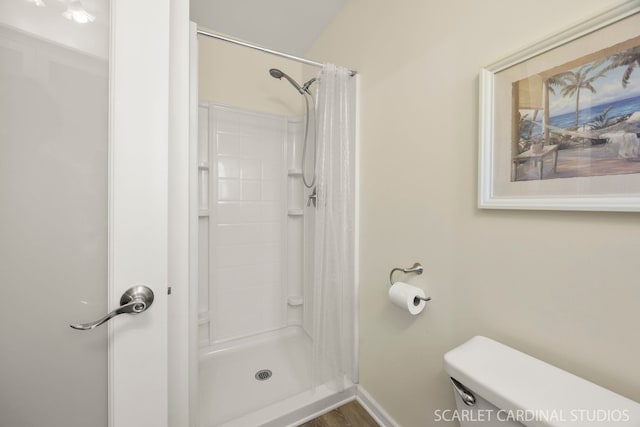 full bathroom with a stall shower, toilet, and baseboards
