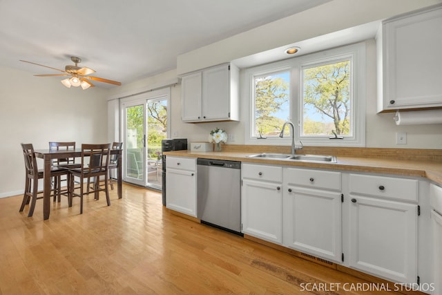 kitchen featuring dishwasher, a sink, light wood finished floors, light countertops, and ceiling fan