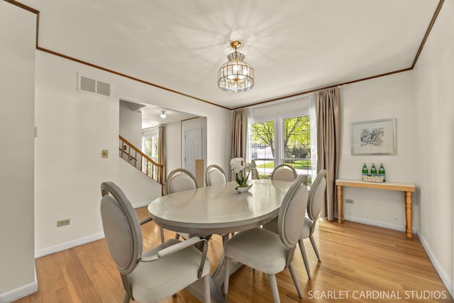 dining area with baseboards, light wood-style floors, a chandelier, ornamental molding, and stairway