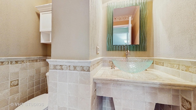 190 Washo Ct, Lake Zurich, IL 60047 - bathroom with a sink, toilet, a textured wall, tile walls, and a wainscoted wall