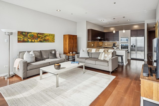 living room with dark wood-style floors and recessed lighting