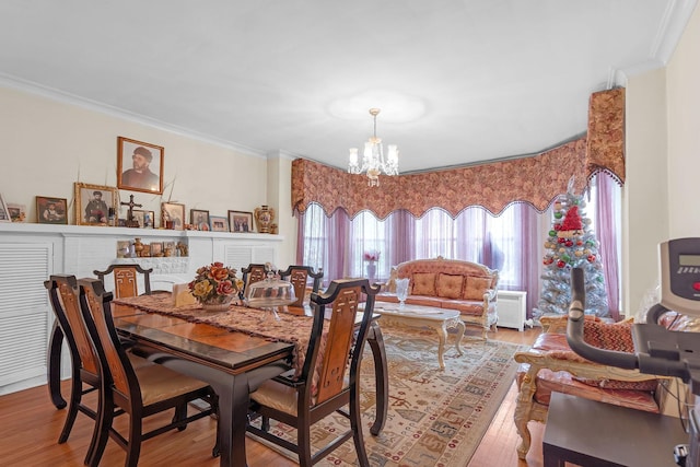 dining area with a chandelier, crown molding, and wood finished floors