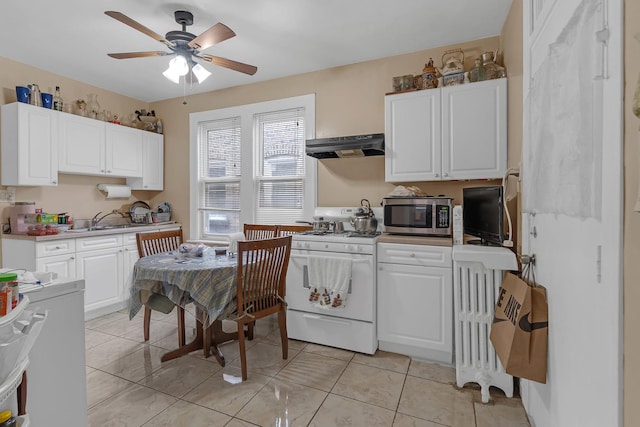 kitchen with white gas range, stainless steel microwave, under cabinet range hood, white cabinetry, and ceiling fan