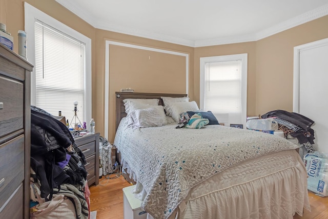 bedroom with light wood-type flooring and crown molding
