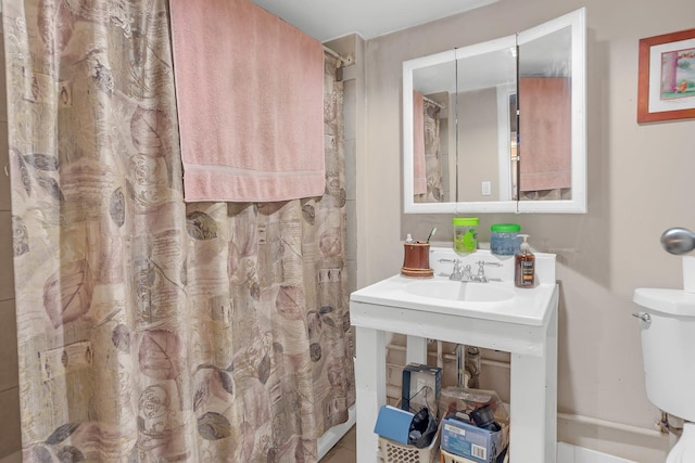 bathroom featuring a shower with shower curtain, a sink, and toilet