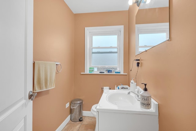 half bathroom featuring baseboards, tile patterned floors, vanity, and toilet