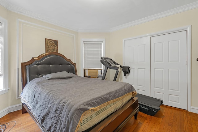 bedroom featuring light wood-style flooring, crown molding, a closet, baseboards, and cooling unit