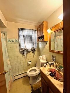 7502 W 64th St, Summit, IL 60501 - full bathroom with tile walls, baseboard heating, toilet, vanity, and a shower with shower curtain