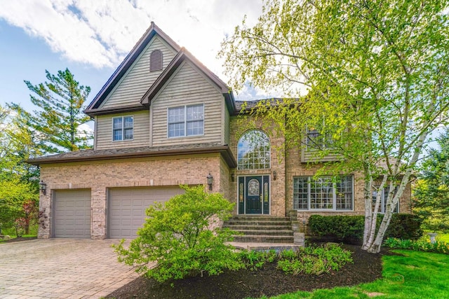 traditional-style house featuring an attached garage, brick siding, and driveway