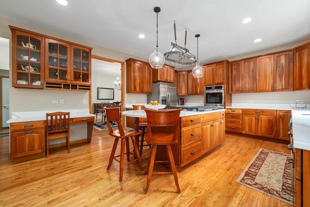 kitchen with appliances with stainless steel finishes, a kitchen island, light countertops, light wood-style floors, and a breakfast bar area
