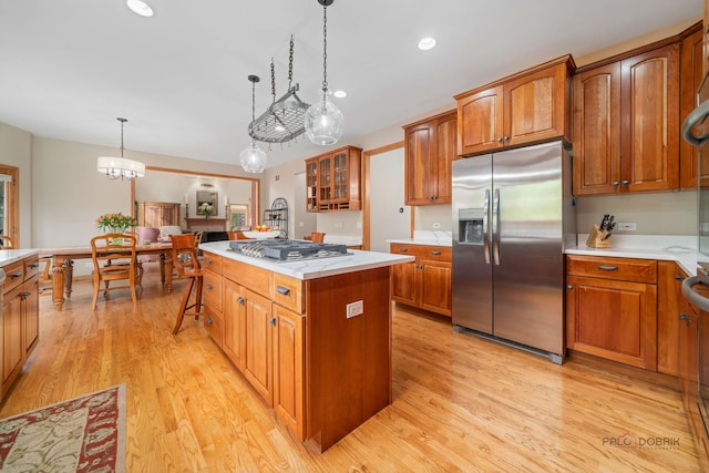 kitchen featuring stainless steel appliances, a kitchen island, light wood-style floors, brown cabinetry, and recessed lighting