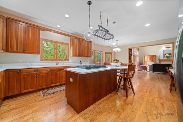 kitchen with stainless steel gas cooktop, a center island, light countertops, a breakfast bar area, and light wood-style flooring