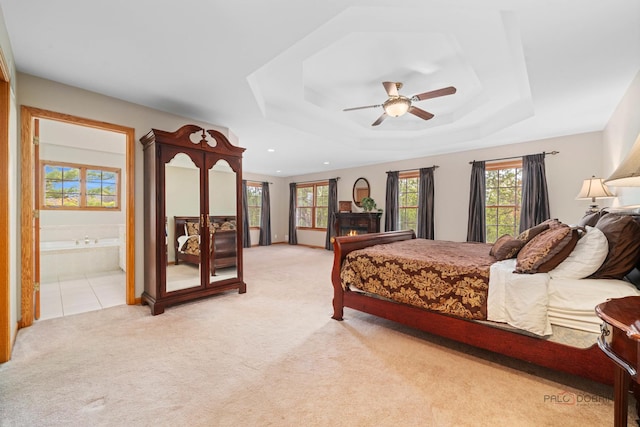 carpeted bedroom with a tray ceiling, connected bathroom, ceiling fan, and recessed lighting
