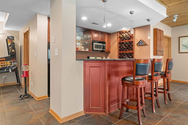 indoor bar featuring stainless steel microwave, baseboards, recessed lighting, and decorative light fixtures