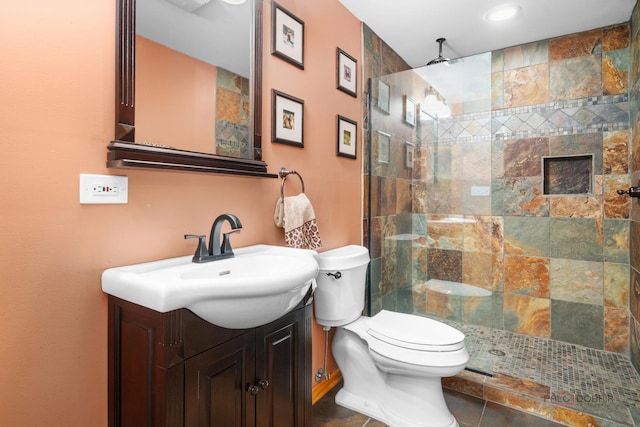 full bathroom with tiled shower, toilet, and vanity