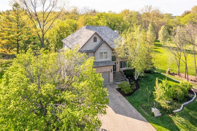 view of front of property featuring decorative driveway, an attached garage, and a front yard