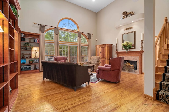 living room with a towering ceiling, wood finished floors, stairway, and a premium fireplace