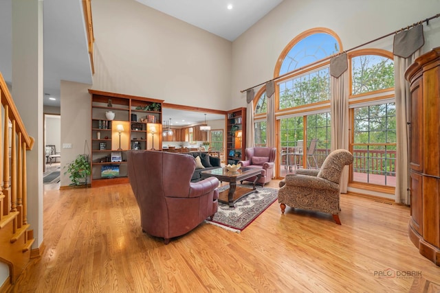 living area featuring light wood-style floors, a high ceiling, stairway, and recessed lighting