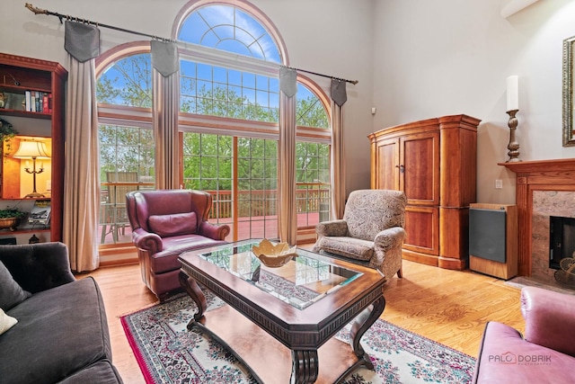 living area with light wood-style floors, a premium fireplace, and a high ceiling