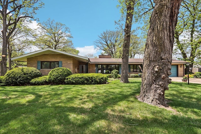 single story home featuring a front lawn, brick siding, a chimney, an attached garage, and driveway