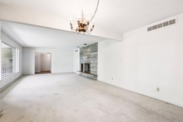 unfurnished living room featuring a chandelier, carpet flooring, and a stone fireplace