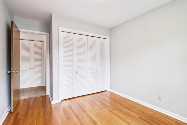 unfurnished bedroom with light wood-style flooring, baseboards, and a closet