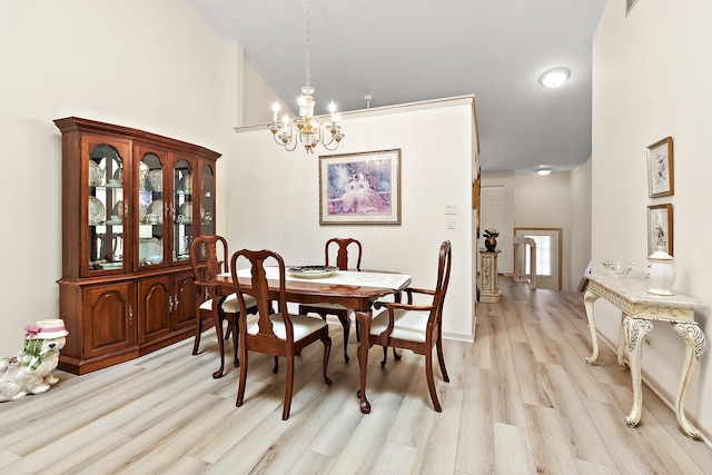 dining area featuring a chandelier, light wood-style flooring, and a towering ceiling