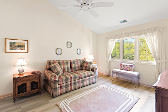 living room featuring lofted ceiling, light wood-style flooring, ceiling fan, and baseboards