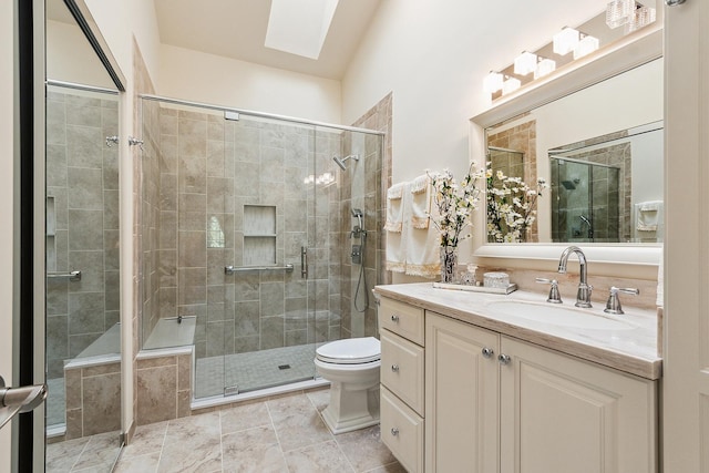 bathroom with a skylight, a stall shower, vanity, and toilet