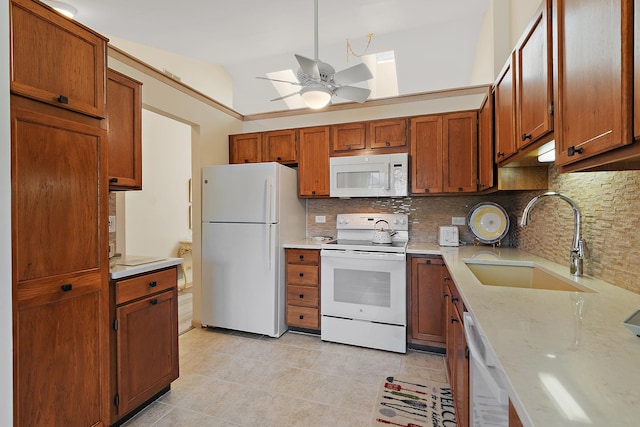 kitchen featuring white appliances, a sink, tasteful backsplash, ceiling fan, and vaulted ceiling