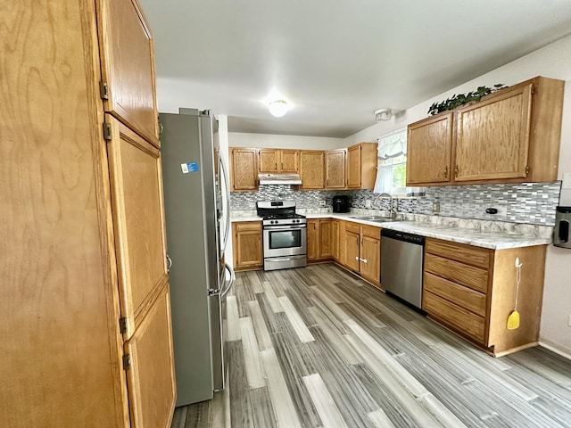 815 S Oak St, West Chicago, IL 60185 - kitchen featuring appliances with stainless steel finishes, a sink, under cabinet range hood, light countertops, and brown cabinets
