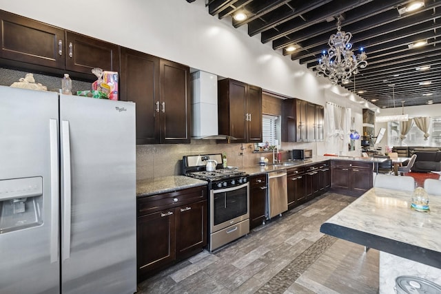 5127 S Artesian Ave, Chicago, IL 60632 - kitchen with stainless steel appliances, wall chimney exhaust hood, a chandelier, and dark brown cabinetry