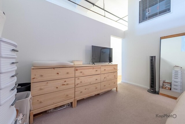 bedroom featuring a high ceiling, light carpet, baseboards, and a skylight