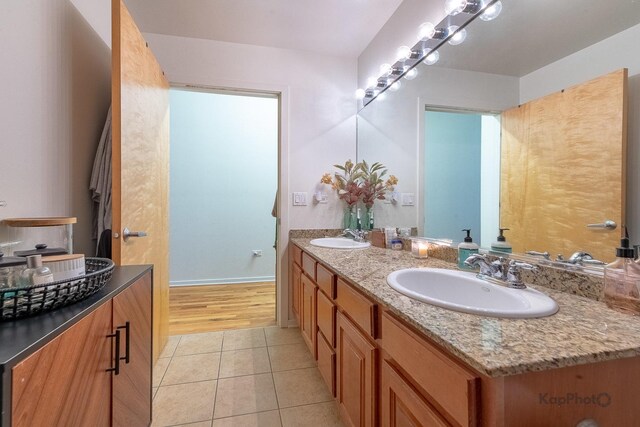 full bathroom featuring tile patterned flooring, double vanity, and baseboards