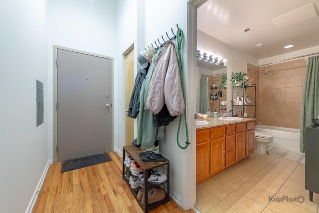 full bath featuring vanity, electric panel, shower / bathtub combination with curtain, tile patterned floors, and toilet