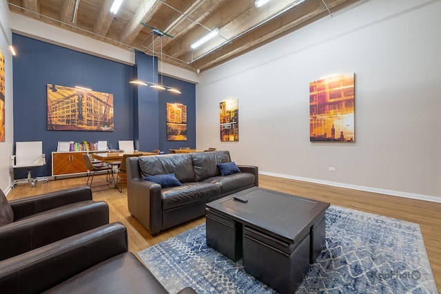 living area featuring wood finished floors, baseboards, and a high ceiling