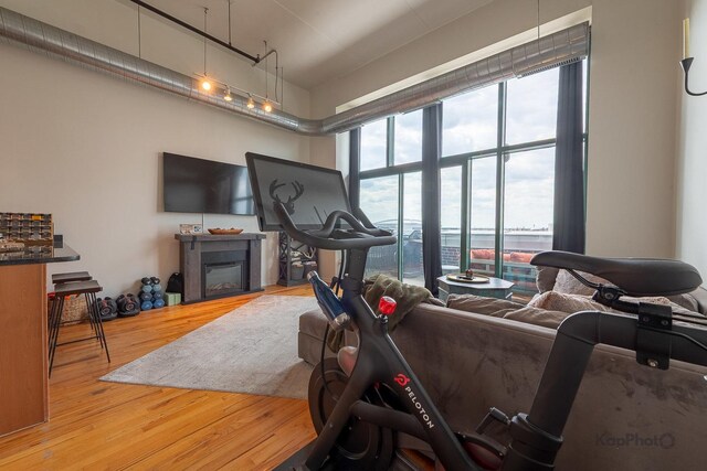 workout area with wood finished floors, a glass covered fireplace, and a towering ceiling