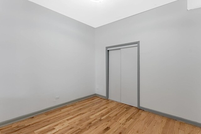 6602 S Marquette Ave, Chicago, IL 60637 - unfurnished bedroom featuring light wood-style floors, a closet, and baseboards