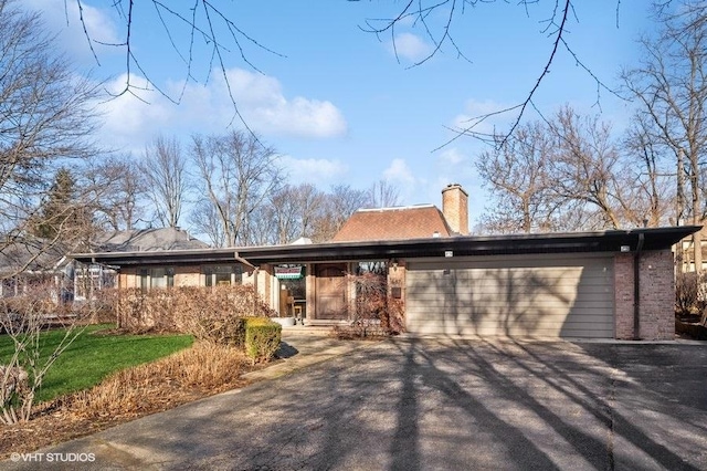 687 Birch Rd, Glencoe, IL 60022 - view of front facade featuring an attached garage, a chimney, asphalt driveway, and brick siding