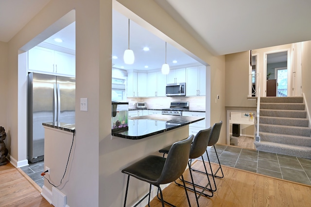 741 E Division St, Lombard, IL 60148 - kitchen featuring appliances with stainless steel finishes, a kitchen breakfast bar, white cabinetry, wood finished floors, and recessed lighting