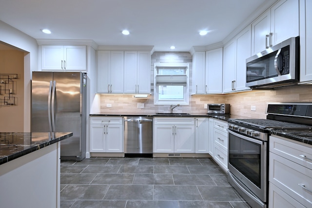 741 E Division St, Lombard, IL 60148 - kitchen featuring appliances with stainless steel finishes, white cabinetry, a sink, tasteful backsplash, and dark tile patterned floors