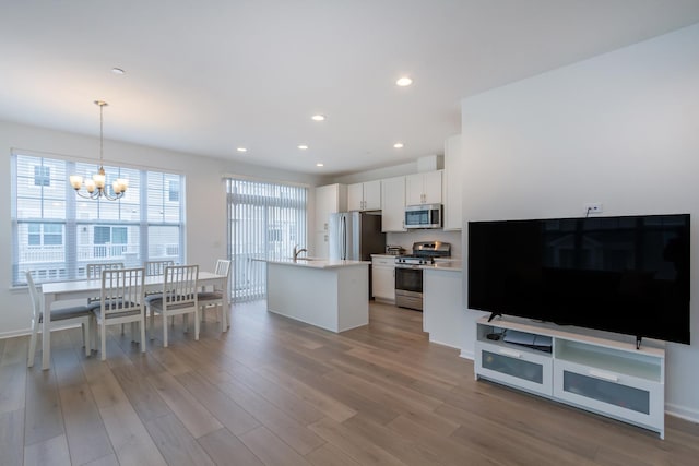 kitchen with appliances with stainless steel finishes, light wood-style flooring, white cabinets, a chandelier, and light countertops
