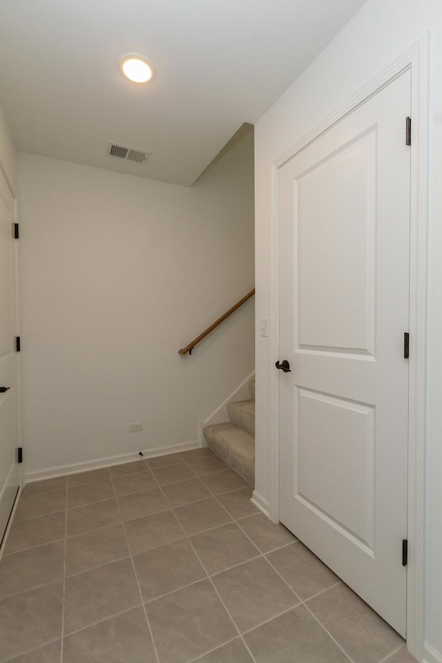 stairway with baseboards and tile patterned floors
