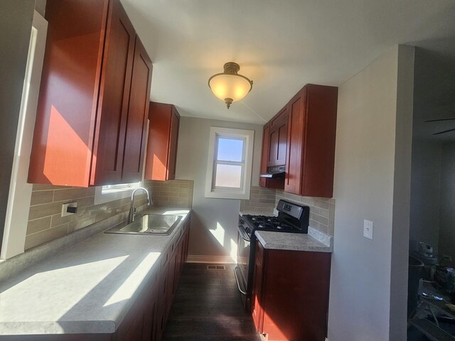 442 Hickory Pl, Elgin, IL 60120 - kitchen featuring black range with gas stovetop, a sink, under cabinet range hood, dark wood-style floors, and backsplash