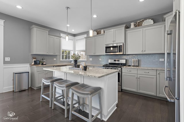 16436 S Mueller Cir, Plainfield, IL 60586 - kitchen featuring stainless steel appliances, a center island, a breakfast bar area, dark wood finished floors, and wainscoting