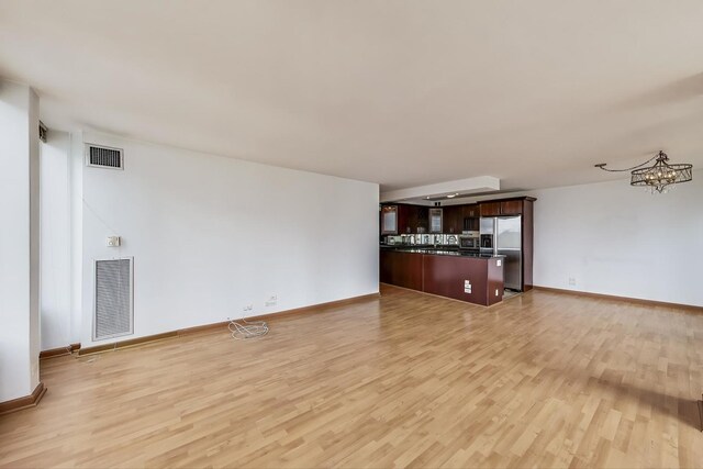 100 E Walton St Unit 25F, Chicago, IL 60611 - unfurnished living room featuring light wood-style floors, baseboards, and a chandelier